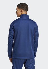 Marineblaues langärmliges Sportoberteil mit hohem Kragen und Raglanärmeln. Glattes, leichtes Material mit tailliertem Schnitt und minimalen Nähten.