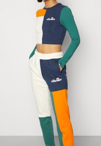 Värgfärgad crop top och joggers i marinblått, grönt, orange och vitt. Har logotypdetalj och elastisk midja; tillverkad av mjukt tyg.