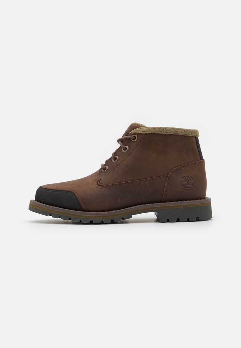 Botas de cuero marrón hasta el tobillo con una punta de goma, cordones redondos y un suave cuello verde. Suelas texturizadas diseñadas para proporcionar tracción.