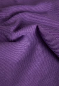 Violetti ribbi-kangas, jossa on teksturoitu pinta, pehmeitä laskoksia ja poimuja, korostaen sen väriä ja materiaaliyhdistelmää.