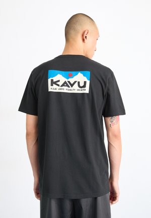 Camiseta de algodón negra con un colorido logotipo gráfico en la parte posterior. El diseño incluye montañas, un sol y texto en un marco rectangular.