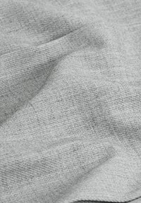 Zacht lichtgrijs stof met een subtiele diagonale weeftextuur, weergegeven in zachte plooien en close-up detail.