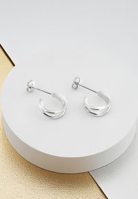 Boucles d'oreilles en argent avec un design courbé et lisse, et une finition polie. Les tiges disposent d'un mécanisme de fixation sécurisée pour un port facile.
