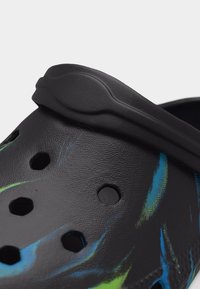 Μαύρο ξύλινο παπούτσι με τρύπες αερισμού και μπλε-πράσινες αφηρημένες ρίγες, με ρυθμιζόμενο λουράκι στη φτέρνα από υλικό με υφή καουτσούκ.