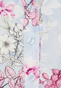 Lys blåt stof med blomstermønster i pink og beige, der har en række hvide knapper langs knapstolpen. Glat tekstur.