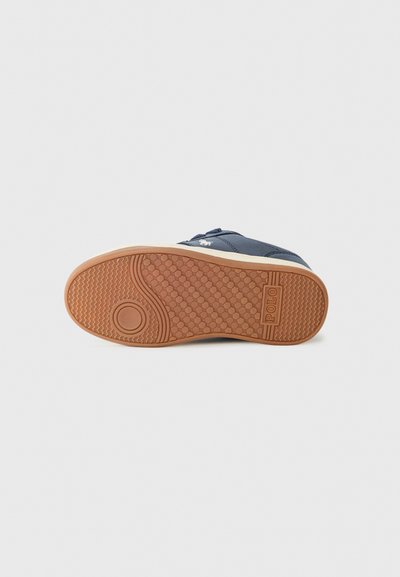 Mörkblå sneakers med en texturerad gummisula, med en krämfärgad mellansula och logodetalj, designade för avslappnad användning och stabilitet.