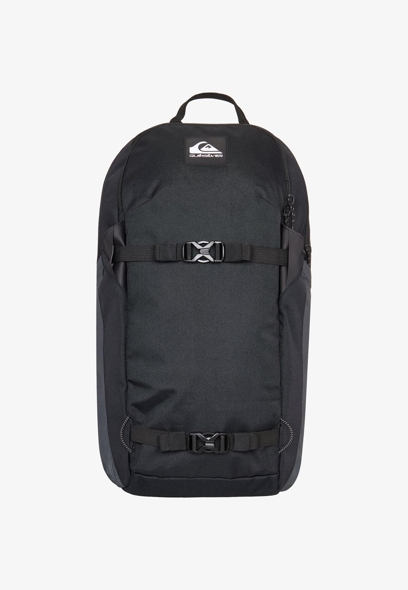 Mochila negra con textura suave, que cuenta con un parche de logo, correas ajustables, cremalleras y hebillas laterales para un cierre seguro.