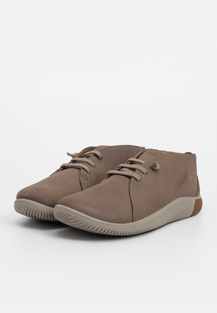 Brązowe skórzane sneakersy z wiązaniem, o okrągłym nosku i teksturowanej beżowej gumowej podeszwie. Posiadają subtelne przeszycia i mały detal z logo.