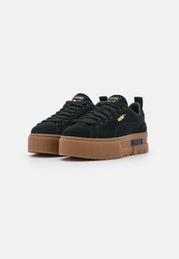 Sneakers platform in suede nero con suola spessa in gomma, dotate di lacci neri e marchio Puma dorato sui lati e sulla linguetta.