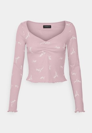 Crop top à manches longues côtelé rose clair avec imprimé floral blanc, encolure en V froncée et ourlet et poignets volantés.