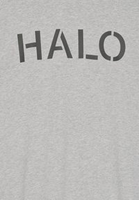 Szary bawełniany T-shirt z wyraźnym czarnym napisem "HALO", gdzie litera "O" jest częściowo otwarta z jednej strony.