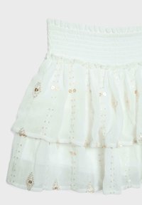 Jupe blanche à étages avec taille élastique, décorée de lignes verticales et de motifs en losange composés de petits sequins dorés.