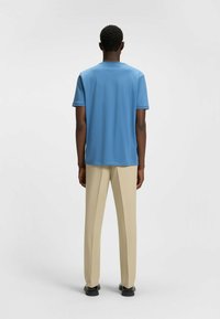 T-shirt azzurro a maniche corte con collo rotondo, abbinato a pantaloni beige. Design semplice con una texture liscia e vestibilità comoda.