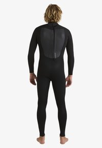 Full-body wetsuit in black, featuring a smooth textured back panel and no zipper design. Tight-fitting sleeves and legs, minimalist design.