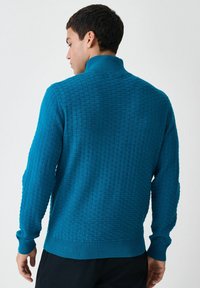 Türkiser Strickpullover mit einem strukturierten, karierten Muster, Stehkragen und gerippten Bündchen. Weicher Stoff mit einem taillierten Design.