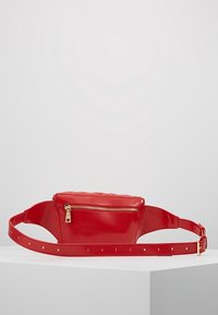 Červená lakovaná bum bag s prošívaným designem a přední kapsou na zip, s nastavitelným popruhem a zlatými kovovými detaily.