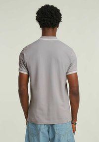Szary polo z krótkim rękawem o slim fit, z białymi akcentami na kołnierzu i rękawach, wykonany z gładkiej tkaniny bawełnianej.
