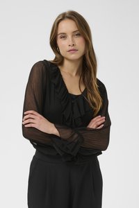 Blusa nera con maniche lunghe trasparenti arricciate e scollo a V. Il tessuto ha un aspetto strutturato, abbinato a un top di colore solido sotto.