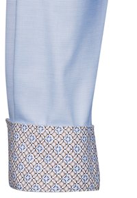 Polsino di camicia a motivi blu, realizzato in un tessuto azzurro con texture e una stampa floreale a contrasto in blu e marrone sul polsino.
