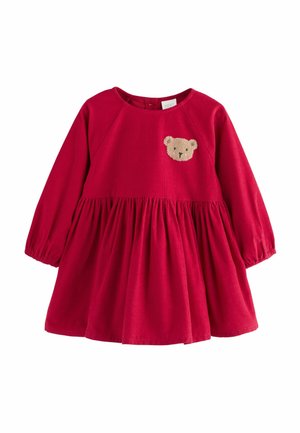 Rotes Corduroykleid mit langen Ärmeln, gerafftem Rock und einem Bären-Applikation auf der Brust. Rundhalsausschnitt und elastische Bündchen.