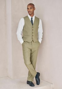 Meeste oliivirohelisest linast vest ja sobivad püksid, valge särk, mustriga lips ning mustad paeltega jalanõud; sile tekstuur ja kohandatud disain.