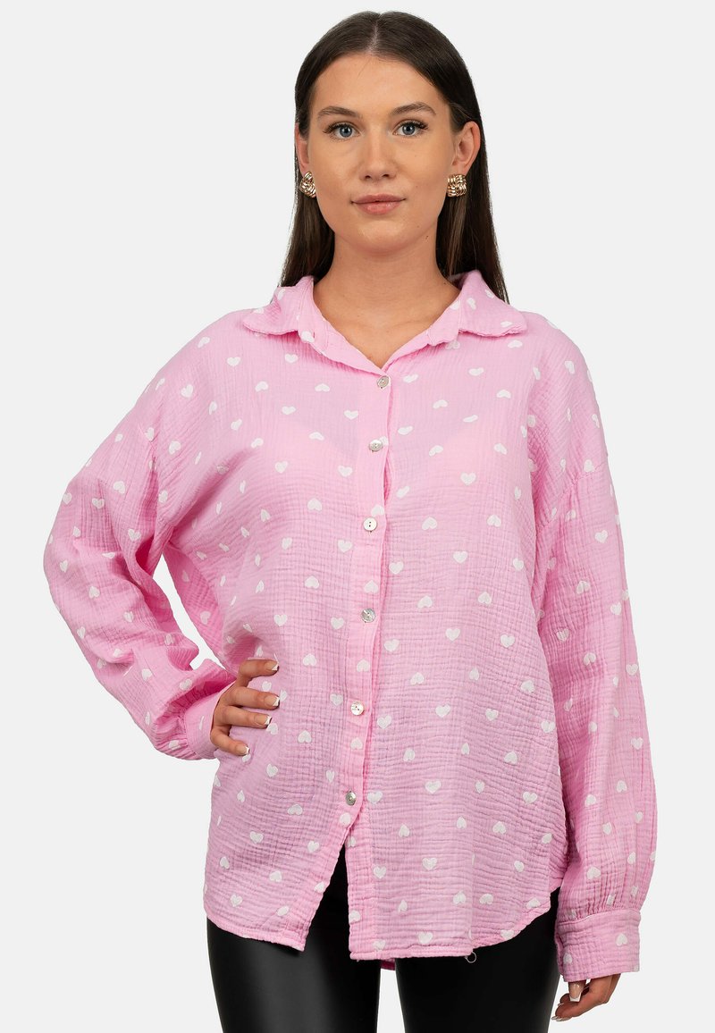 Camicia button-up rosa realizzata in tessuto morbido, con un design testurizzato con motivi a cuori bianchi e un colletto classico. Maniche lunghe e larghe.