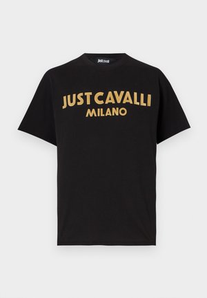 Black cotton t-shirt with short sleeves. Features large gold text reading "JUST CAVALLI MILANO" across the chest in a curved design.
