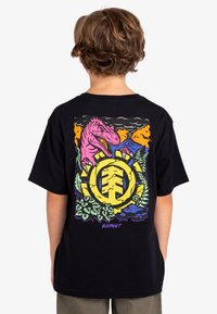 Camiseta negra de manga corta con gráficos vibrantes de dinosaurios y naturaleza en rosa, amarillo y verde. Logotipo distintivo de la marca en el centro.