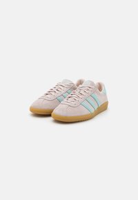 Light pink suede sneakers with turquoise stripes and a gum rubber outsole. Features lace-up closure and rounded toe design.