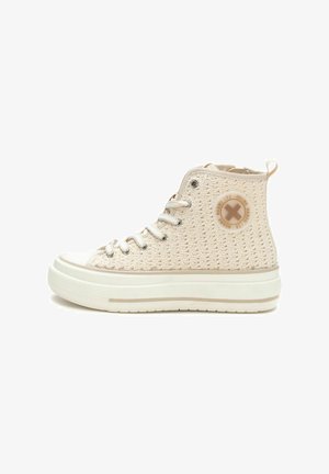 Zapatillas altas color beige hechas de tela tejida. Cuentan con cordones, un logo circular en el lateral y una suela de goma blanca gruesa con una franja beige.