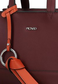 Borsa in pelle bordeaux con tracolla in pelle arancione e hardware in argento. Dotata di attacco a forma di anello e logo impresso.