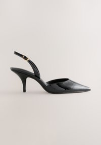 Escarpin à bride arrière en cuir verni noir à talon haut avec bout pointu et boucle dorée sur fond neutre.