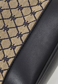 Beige og marineblå mønstret stofhåndtaske med et vævet geometrisk design, kombineret med en glat marineblå syntetisk læderbund.