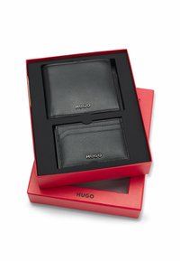 Set van zwarte leren portemonnee en kaarthouder in een rode, merkdoos. De portemonnee heeft een gestructureerd oppervlak; beide items zijn voorzien van een reliëflogo.