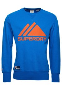 Sudadera azul de algodón, con un gran diseño de triángulo naranja y el texto "SUPERDRY" en naranja. Puños y dobladillo de canalé.