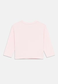 Light pink cropped long-sleeve top, made from soft fabric, with a round neck and hemmed cuffs. Smooth texture, no patterns or accents.