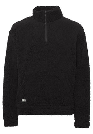 Pullover in pile nero con colletto a zip quarti, superficie texturizzata, tasca frontale e una piccola etichetta con logo sull'orlo.