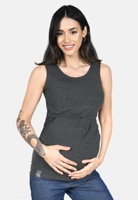 Top premaman grigio con scollatura rotonda e vita impero, realizzato in tessuto morbido. Il modello lo indossa con jeans blu, con le mani sulla pancia.