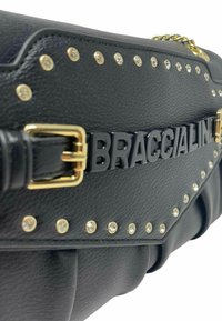 Borsa a tracolla in pelle nera con hardware dorato e dettagli borchiati. Presenta un marchio in lettere in grassetto e una texture trapuntata sui bordi.