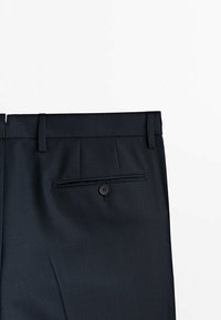 Pantalon gris foncé sur mesure à motif discret à carreaux, doté d'un devant plat, de passants pour ceinture et d'une poche arrière avec fermeture à bouton.