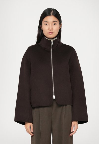 Dunkelbraune kurze Jacke mit hohem Kragen, Reißverschluss vorne und breiten Ärmeln. Hergestellt aus weichem Material mit glatter Textur.
