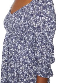 Blomstermönstrad klänning med nyanser av blått och vitt, med en figursydd bodice, puffärmar och en svängande kjol.