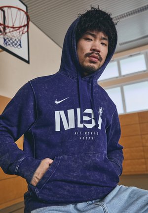 Karbija zils sporta džemperis ar baltu NBA logo un tekstu "VISPASAULĒS GROZAS", ar priekšējo kabatu un šņorējamu kapuci. Tekstūrēta auduma.