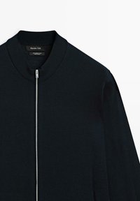 Námornická bombardovací bunda ze 100% merino vlny s žebrovaným límcem a plným zipem. Hladký povrch, minimalistický design a žádné viditelné vzory.
