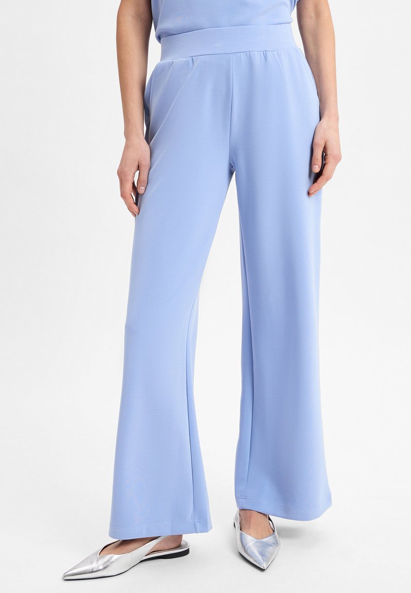 Lichtblauwe wijde broek gemaakt van een gladde, rekbare stof met een hoge tailleband en zakken. Gepaard met metallic zilveren instappers.