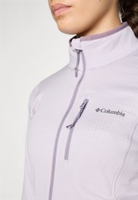 Svijetloplavi zip-up jakna s teksturiranim završetkom, visokim ovratnikom i patentnim zatvaračem na džepu. Sadrži logo Columbia na prsima.