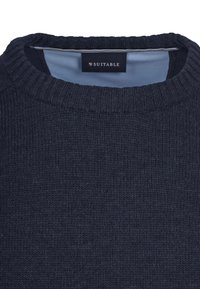 Dunkelmarineblauer gestrickter Pullover mit geripptem Rundhalsausschnitt und hellblauem Innenfutter, mit dem Etikett "SUITABLE" am inneren Nackenschild.
