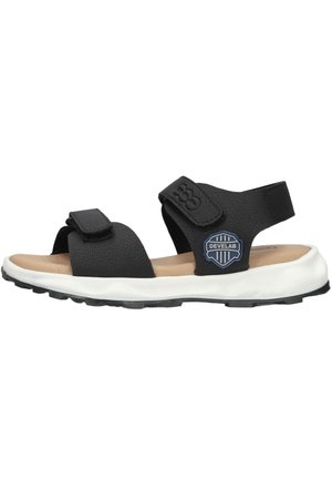 Black open-toe sandal with two adjustable straps, beige footbed, white sole, and a blue Develab logo on the side.