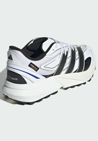 White athletic shoe with black and blue accents, textured material, cushioned sole, and reinforced areas. Features a lacing system and logo.