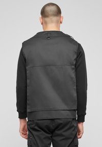 Black jacket with a smooth texture and a layered design. Features a high collar and a metal loop on the back. Tailored fit, minimalist style.